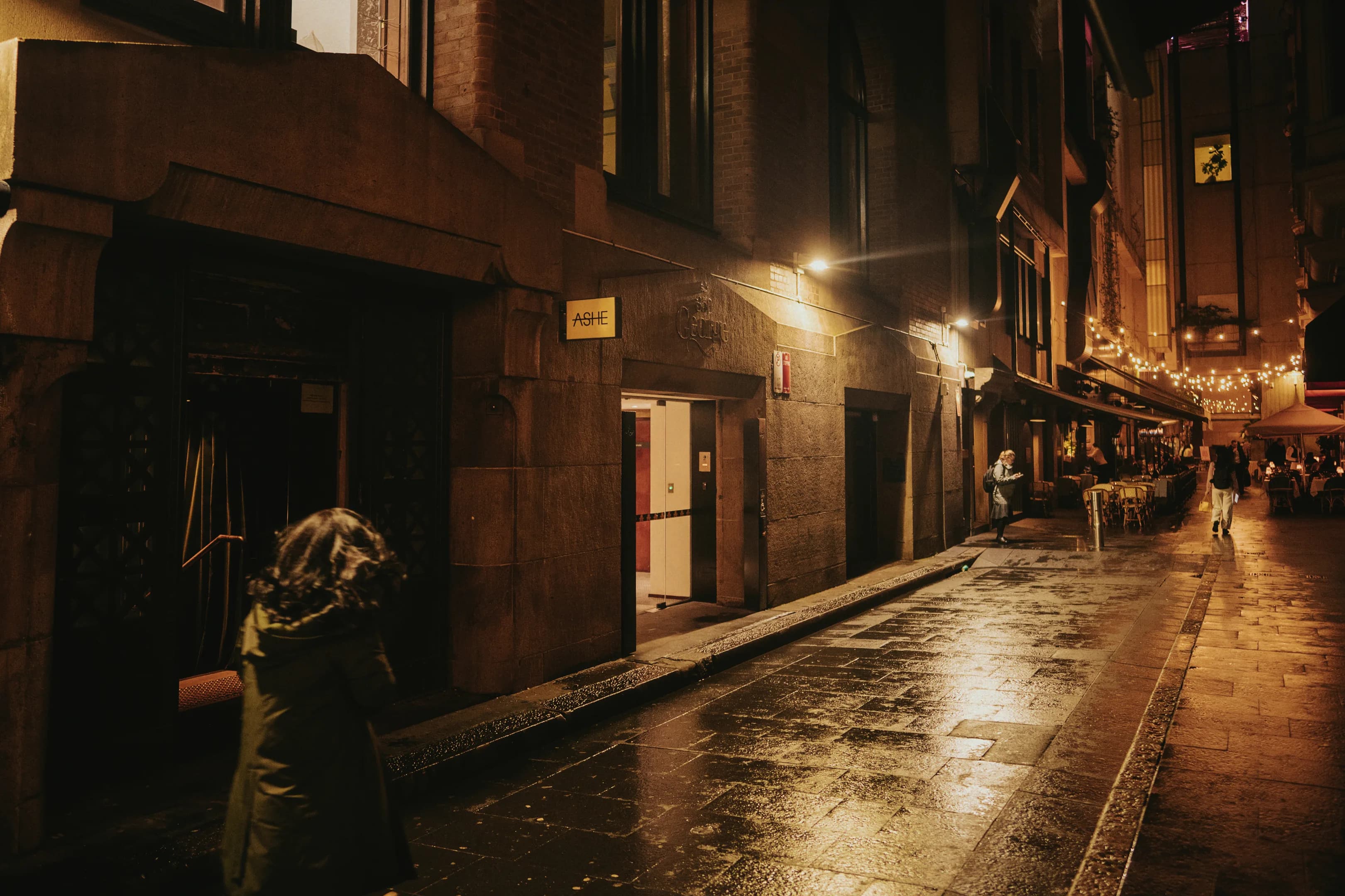 The Ashe entrance on Angel Place at night after rain